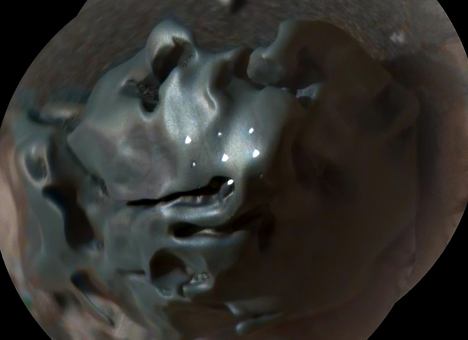 A slightly blurry close view of a small iron meteorite with six small white dots on it from a laser instrument