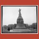 A black-and-white photograph of the Reconciliation Memorial against a red background