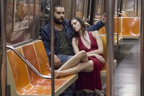 Marnie wears a red dress and leans on Charlie's shoulder in a subway