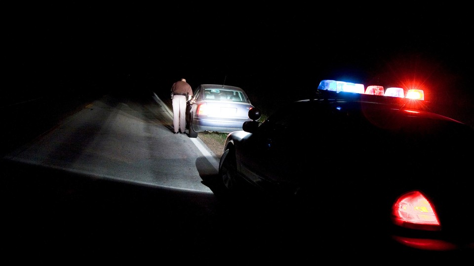 A photo of a police car behind a car that was pulled over at night