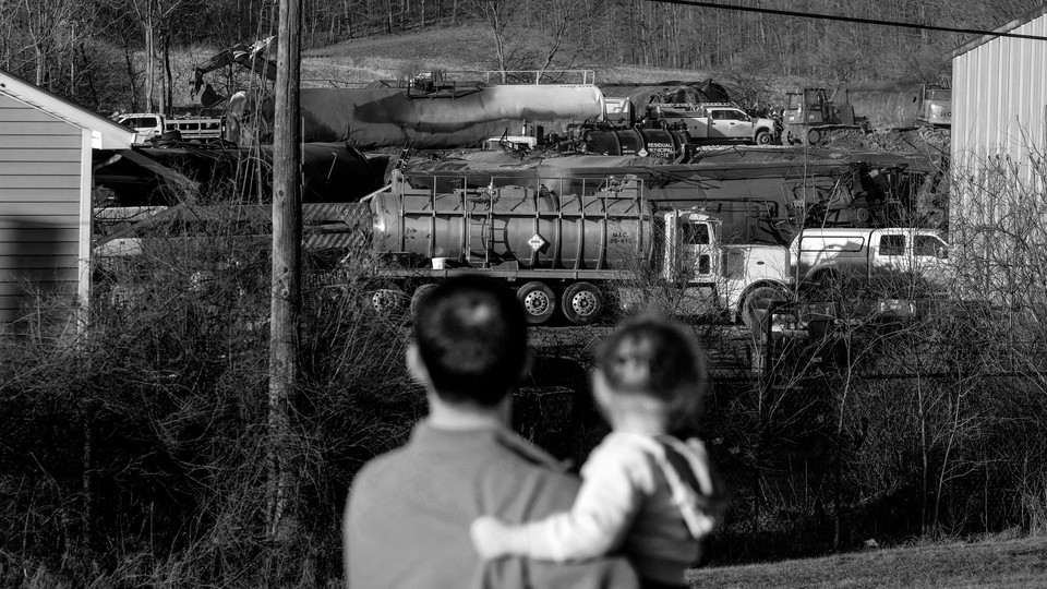 A family looks at the wreck in East Palestine