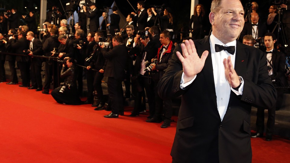 Harvey Weinstein poses on the red carpet with photographers behind him.