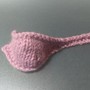 A pink knitted object resembling a ladle