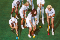 photo of group of croquet players with mallets and balls on green field