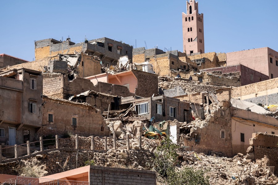 A broad view of many damaged or collapsed houses and other buildings on a hillside.
