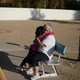 A young child hugs an older person sitting on a park bench.