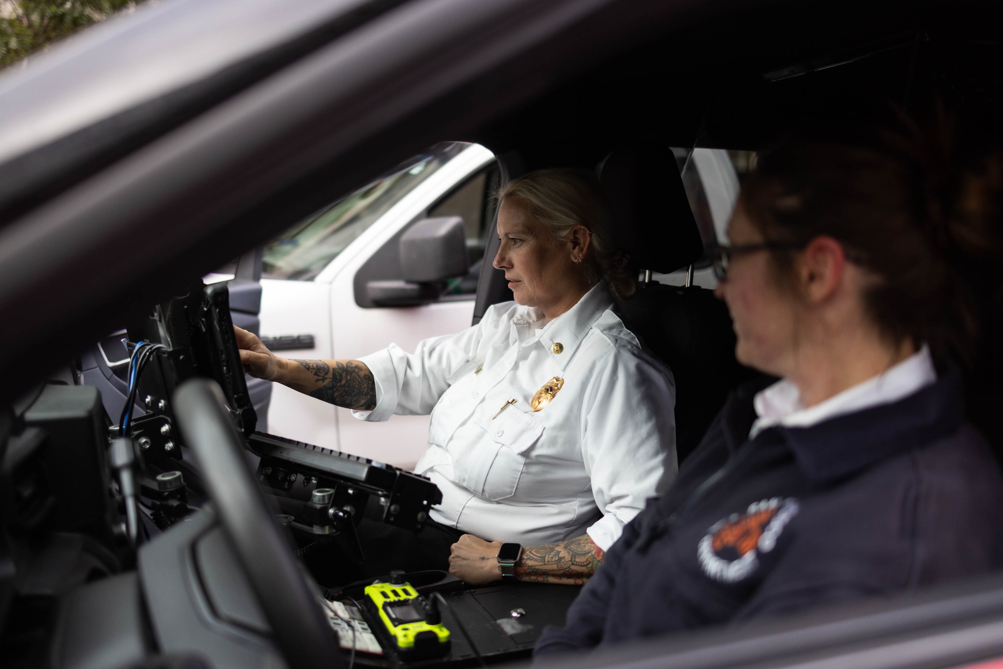 Picture of April Sloan and Sherry Mahoney inside the EMS6 vehicle in San Francisco, California, with Sloan checking a call monitor while Mahoney looks on during their shift.