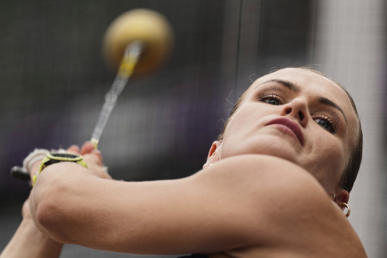 An athlete leans back while swinging a hammer during a hammer-throw competition.