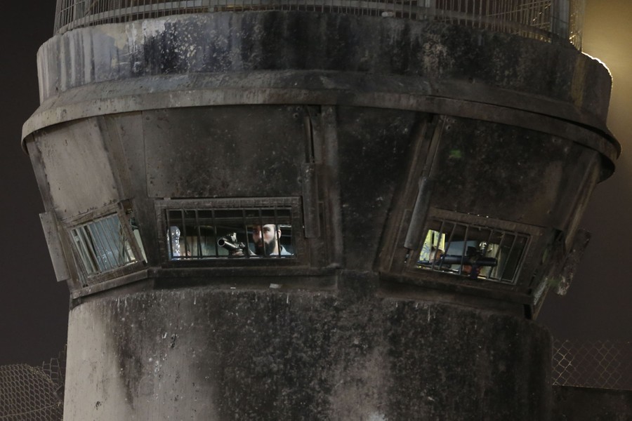 Soldiers in a guard tower point weapons out windows.