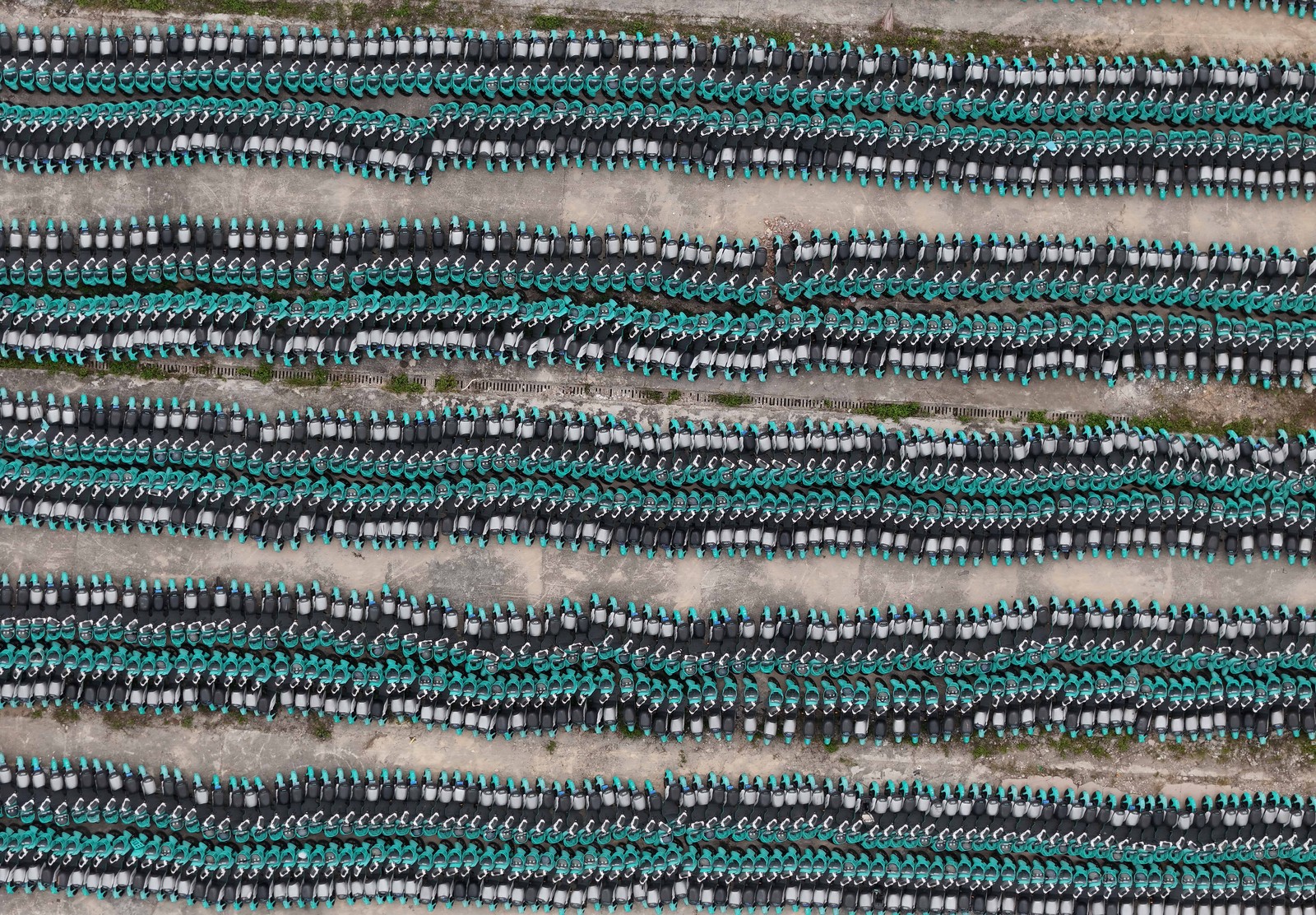 Long densely-packed rows of unused shared electric bicycles, seen from above