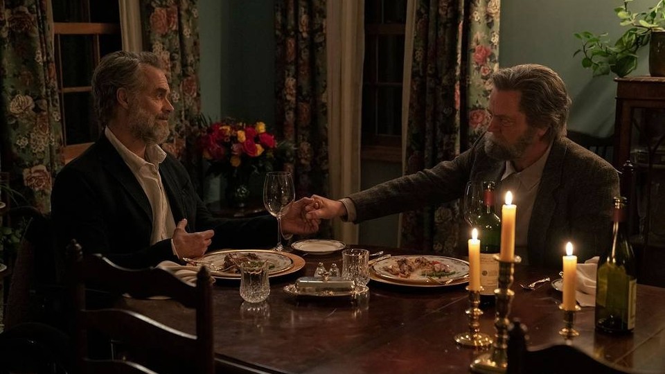 A still from The Last of Us showing two older men holding hands while dining