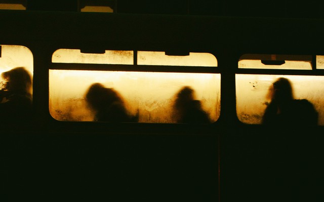 Yellowed windows of a train with 4 silhouettes visible