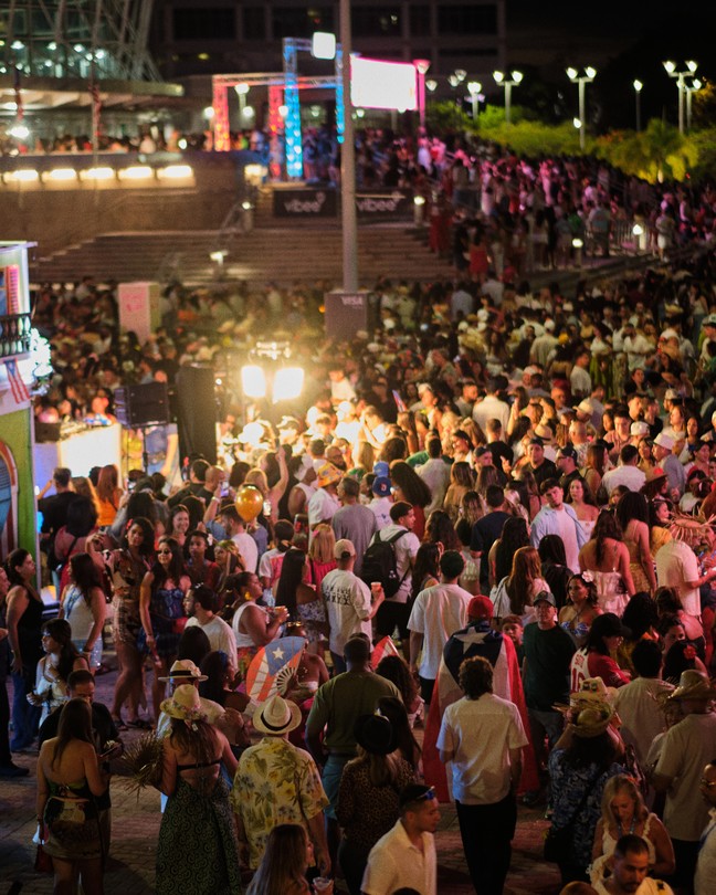 A color photograph of a crowd outside a concert venue at night
