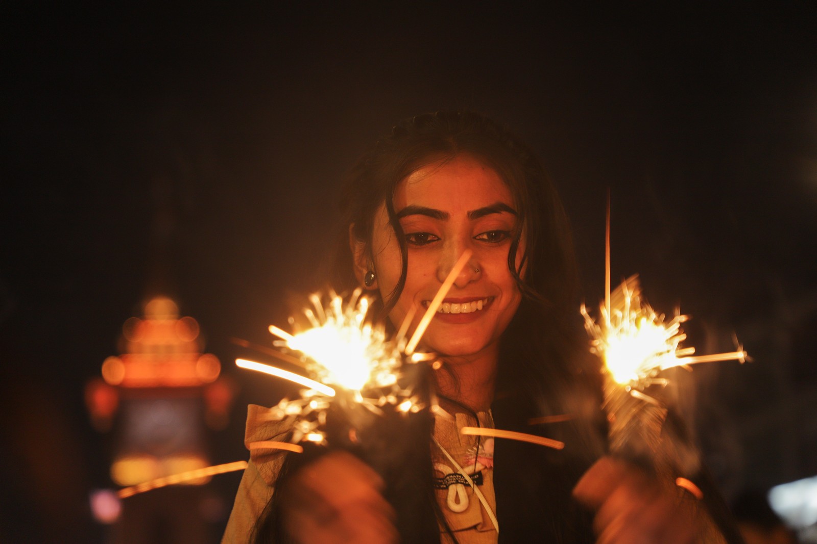 A woman is holding a pair of sparklers.