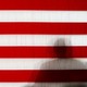 A giant American flag with a shadow of a man imposed on it