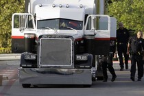 San Antonio police officers investigate the scene where eight people were found dead in a tractor-trailer loaded with at least 30 others outside a Walmart store in stifling summer heat in what police are calling a horrific human trafficking case.