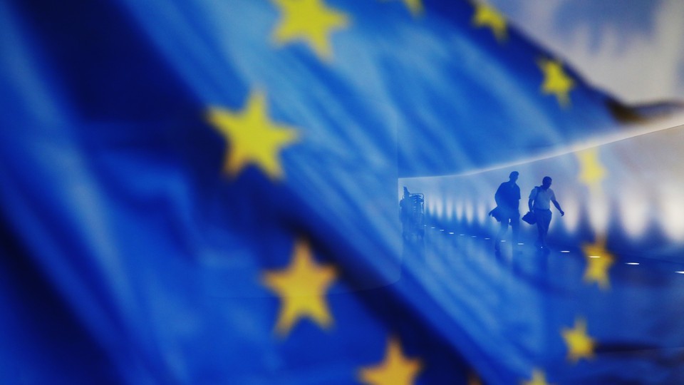 People walk behind a waving flag of the European Union