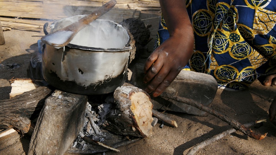 A silver, old, cracked saucepan rests on an open fire 