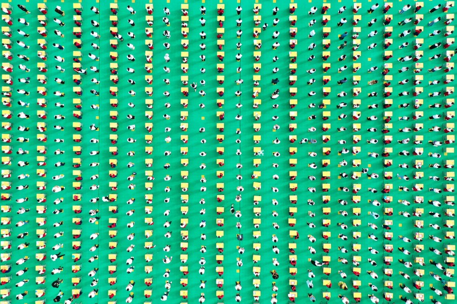 An aerial view of several hundred students and desks arranged in rows