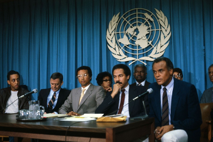 Five men sit at a table in front of microphones during a press conference.