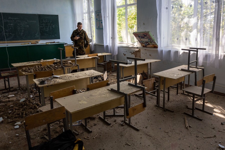A soldier inspects a damaged school classroom.