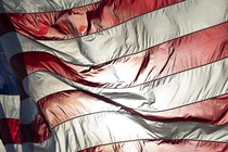 An American flag backlit with sunlight