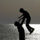The silhouettes of a father and son playing on the beach