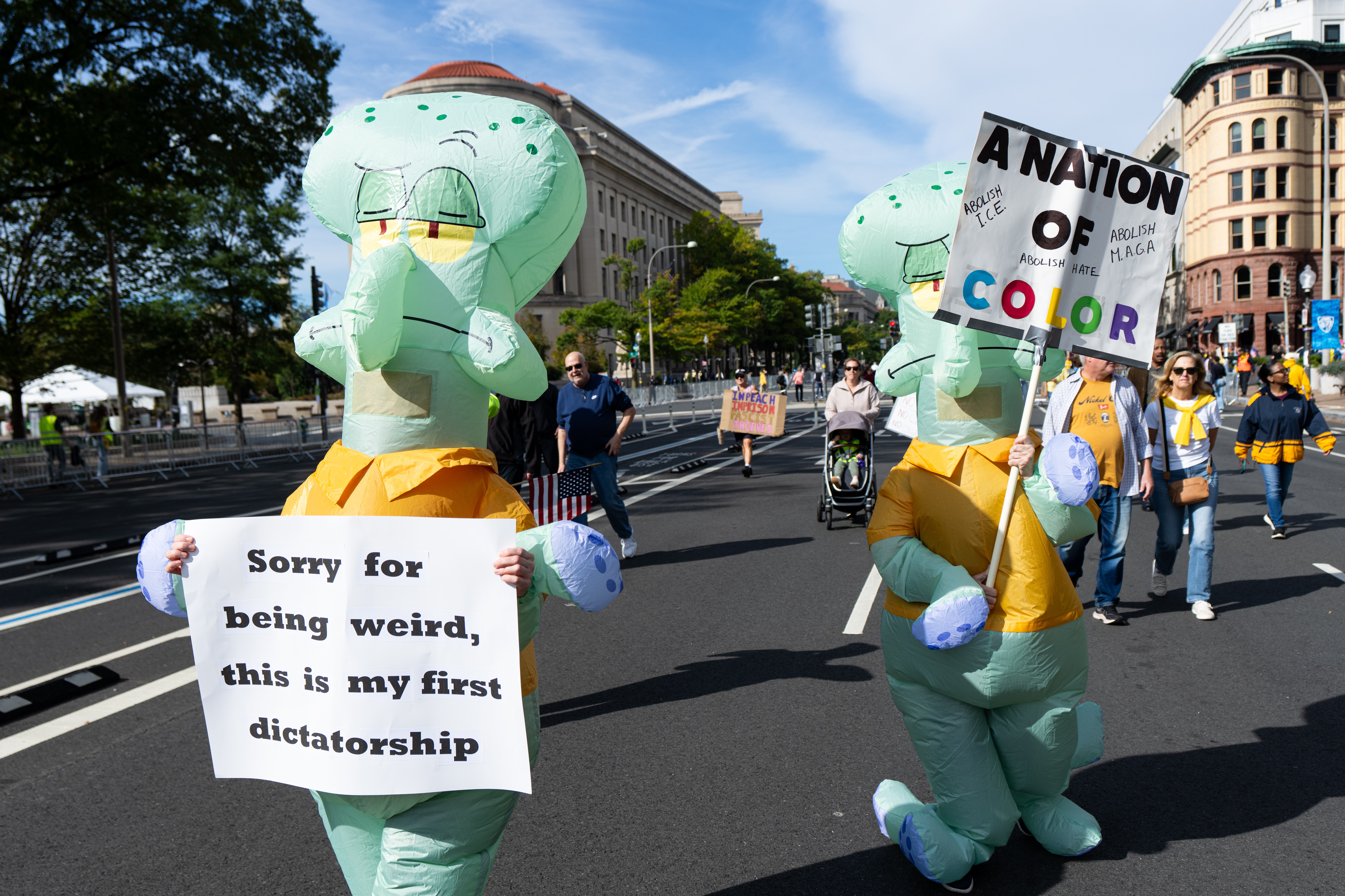 Two protesters wearing inflatable costumes of Squidward, a character from the SpongeBob SquarePants TV show, carry signs, including one that says