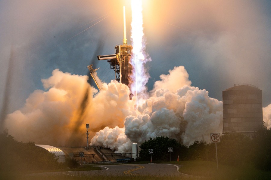 Flames erupt as a rocket launches from a pad.