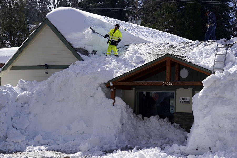 A worker clears deep snow off the roof of a lodge.