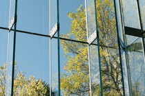 Green trees and a blue sky seen through glass windows