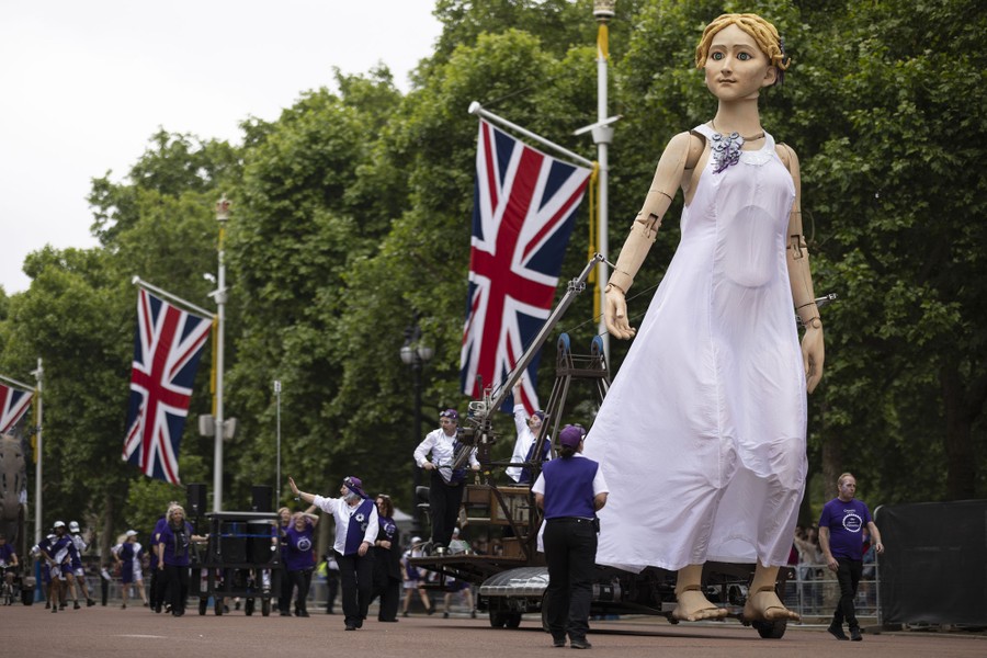 A very tall marionette of a woman is 'walked' by puppeteers during a parade.