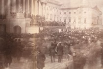 An older photograph showing a crowd (looking blurry due to movement) in front of the U.S. Capitol building during an inauguration ceremony.