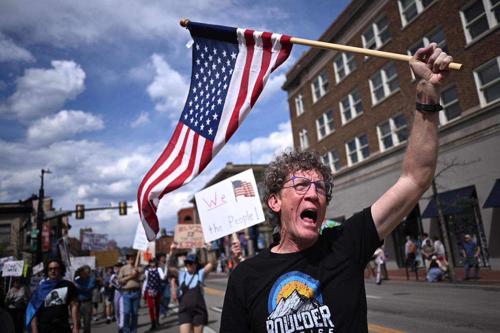 A protester holding an American flag leads a chant in front of other marching protesters.