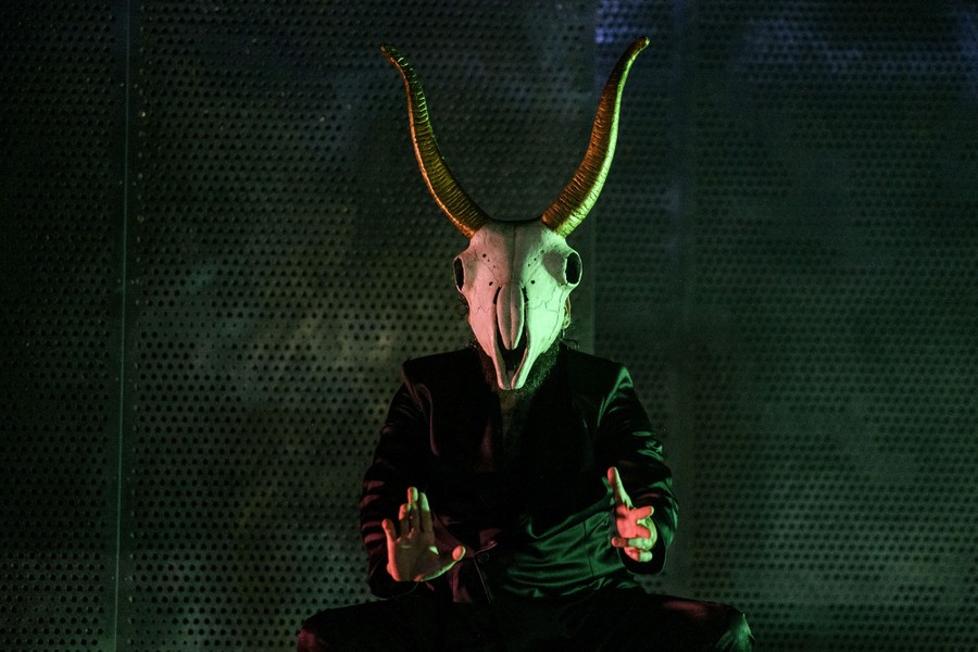 An actor performs onstage wearing an animal-skull costume.