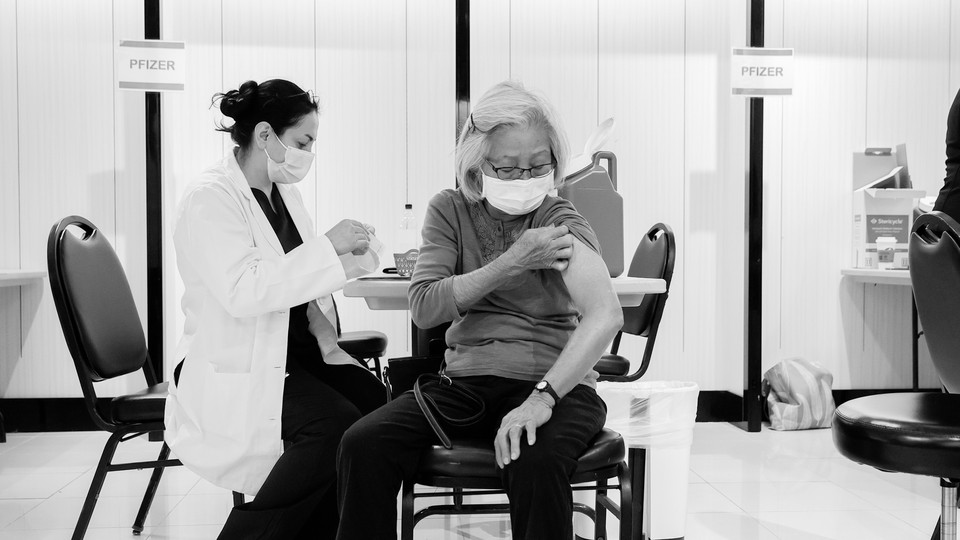 Black-and-white photo of a woman receiving a COVID-19 vaccine