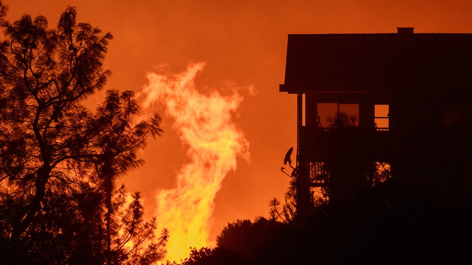 A fire approaches a house; the sky is orange.