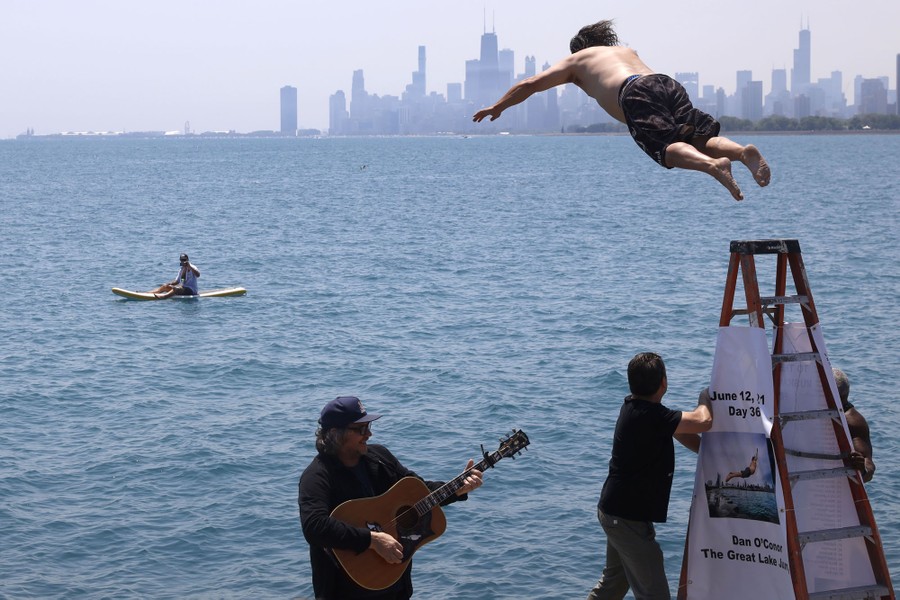 A man leaps from a stepladder, diving into Lake Michigan.
