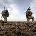 Two soldiers kneel on the ground in Afghanistan.