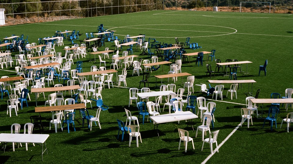 An empty field has lots of empty chairs and tables