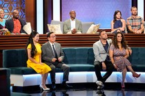Four couples and one single man sit on couches in an amphitheater.