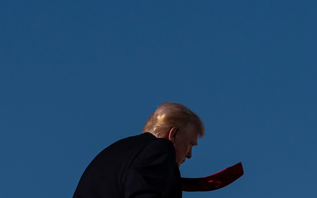 Donald Trump walks away from the camera, his red tie flapping.