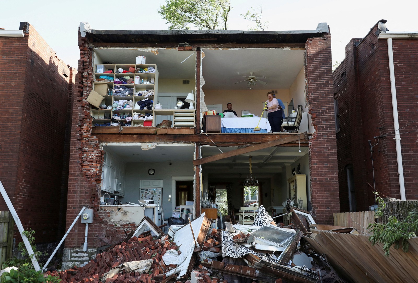 People inspect their home after a tornado completely tore off the back wall of a two-story house