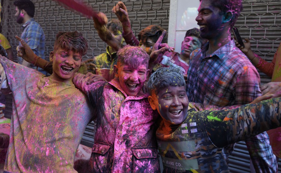A group of boys covered in colored powder laugh together.