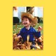 A young boy plays in a pile of leaves.