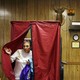 A woman leaves a voting booth with a blue curtain, set in front of hunting trophies, in Danielsville, Pennsylvania