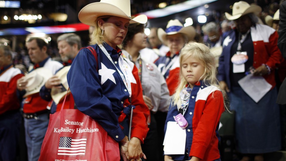 A woman and daughter dressed patriotically bow their heads in prayer