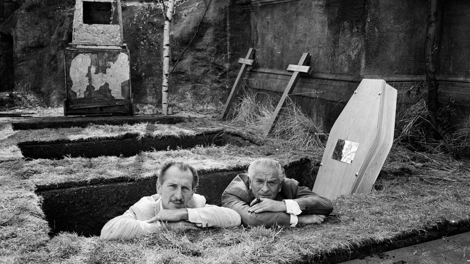 Two men stand in a freshly dug grave.