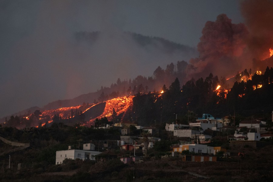 A river of lava approaches houses.