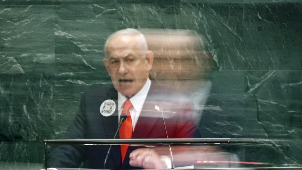 Photograph of Benjamin Netanyahu speaking at the U.N. podium with his image blurred, as if moving quickly